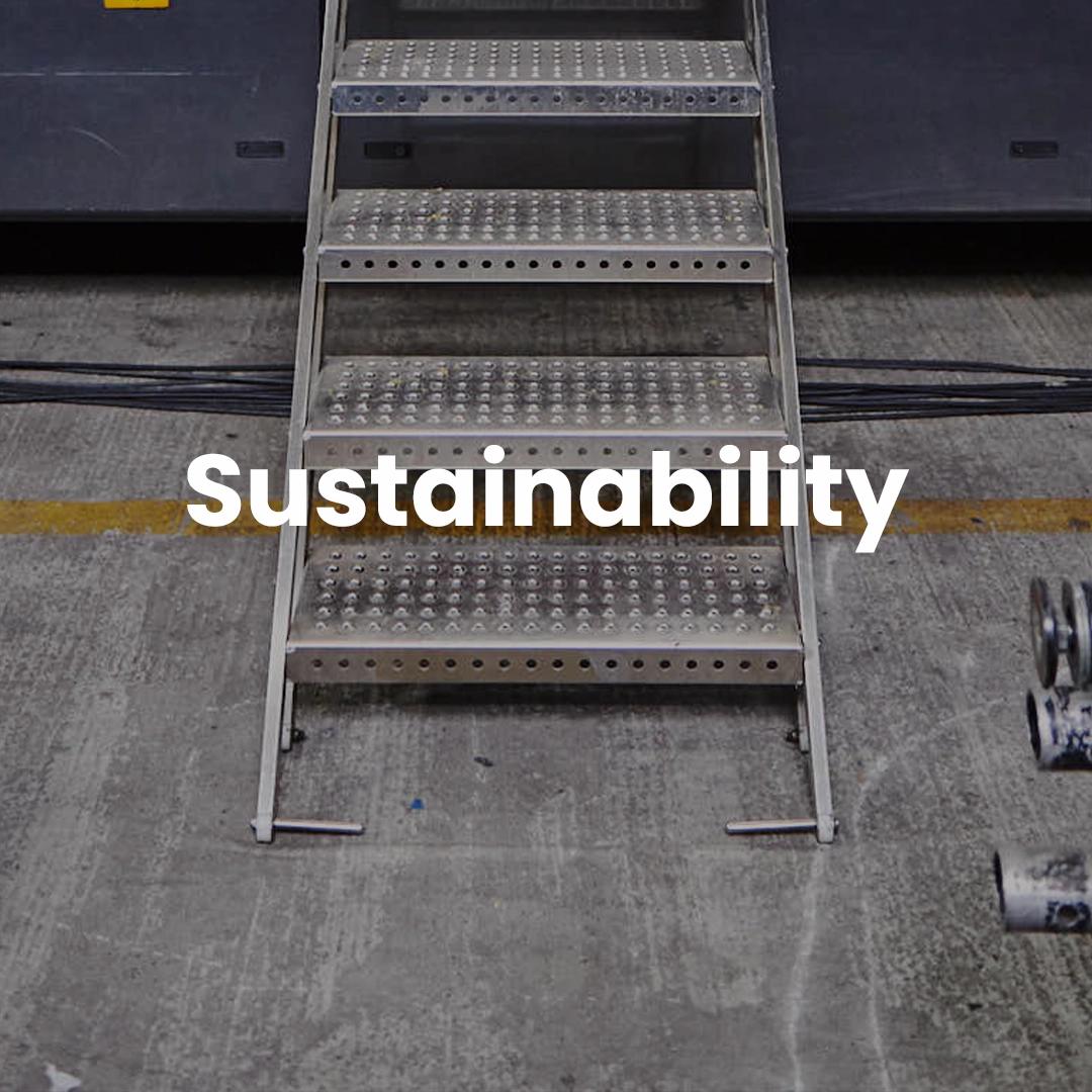 Metal staircase in an industrial facility with the word "sustainability" overlaid in bold white text.