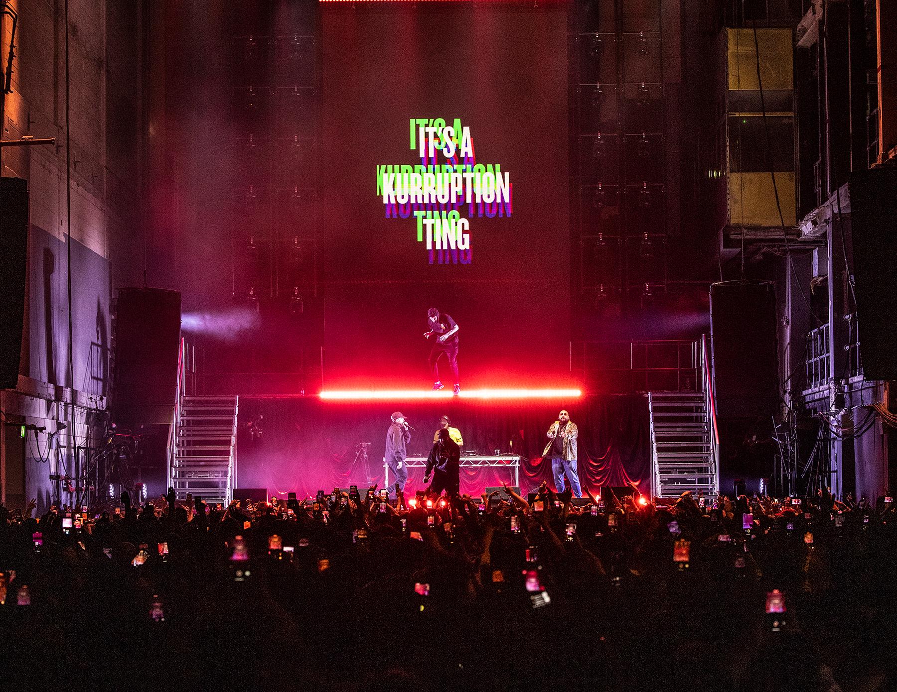 Kurupt FM on stage in front of a screen that says 'its a kuruption thing' at Printworks London 