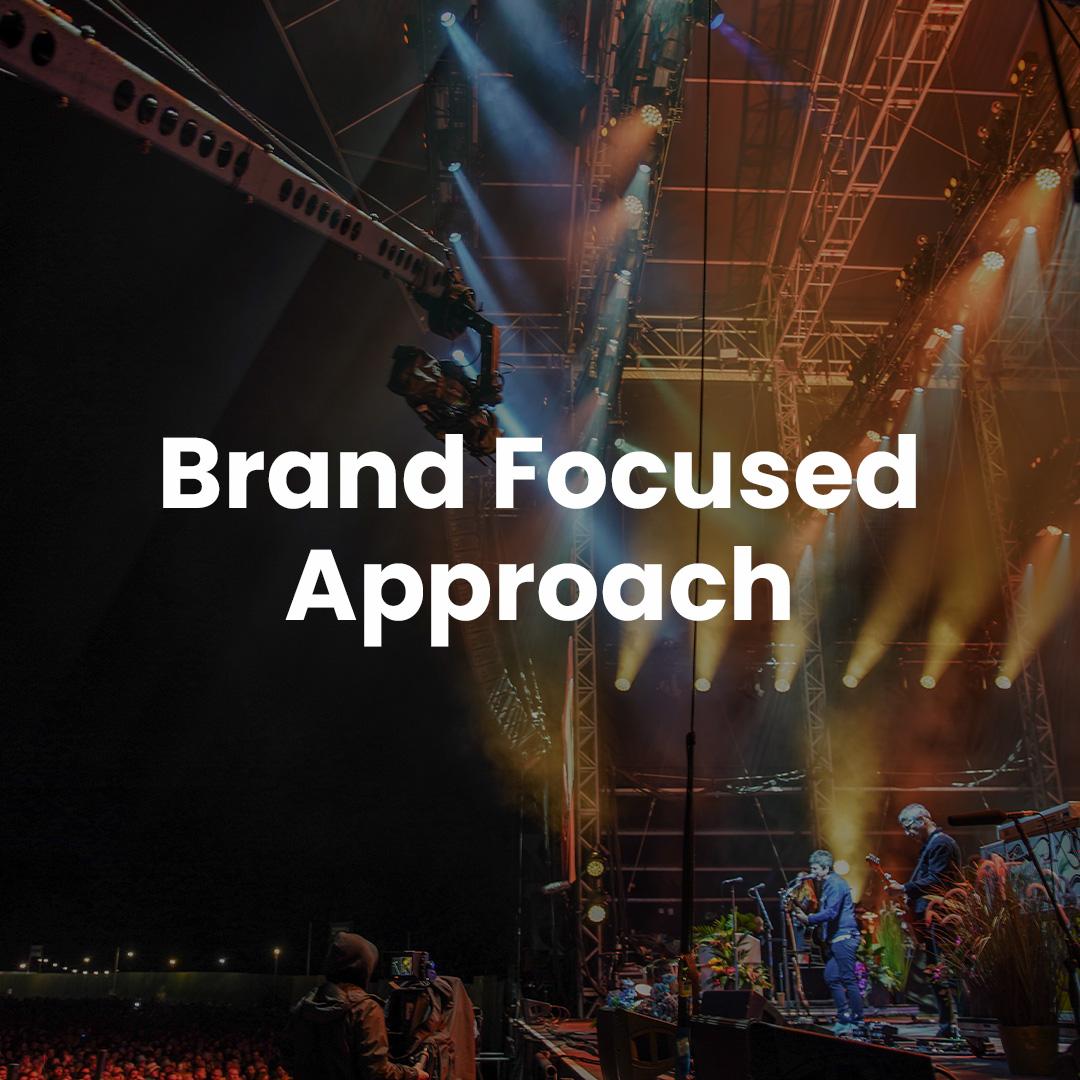 A concert stage with musicians performing, lighting rigs above, and text "brand focused approach" overlaying the image.