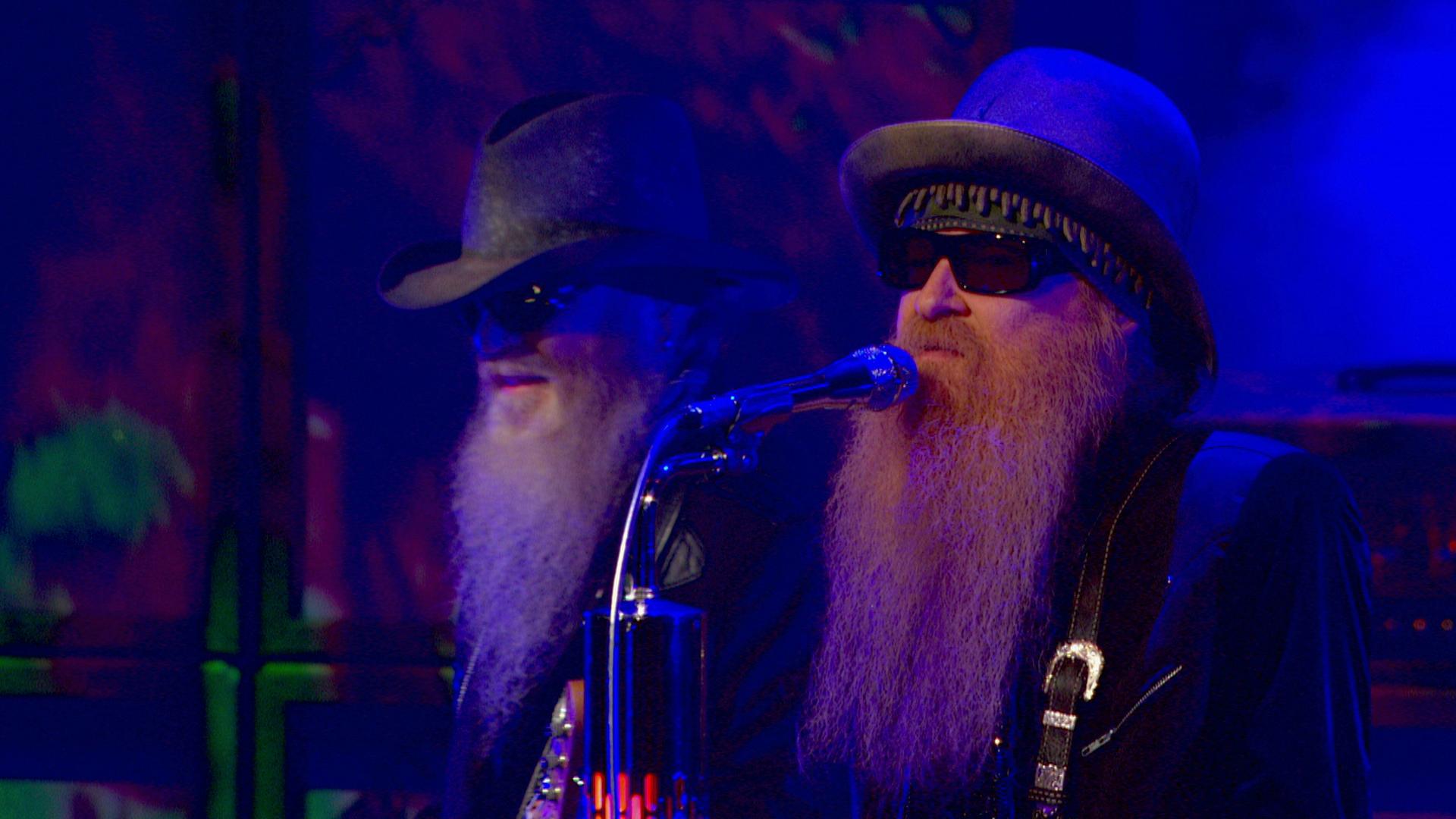 ZZ Top perform on stage under blue and green lighting.