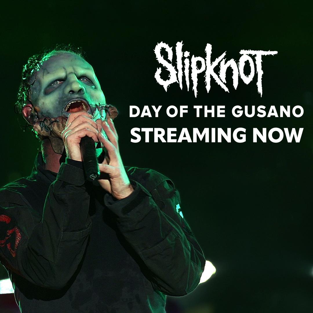 Slipknot frontman a theatrical mask sings into a microphone on stage. Text reads, "Slipknot Day of the Gusano Streaming Now.