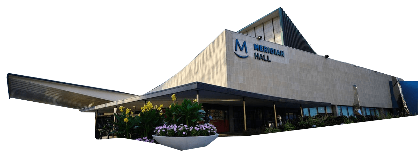 The exterior of Meridian Hall, a modern building with glass towers in the background, landscaped plants, and parked vehicles nearby.