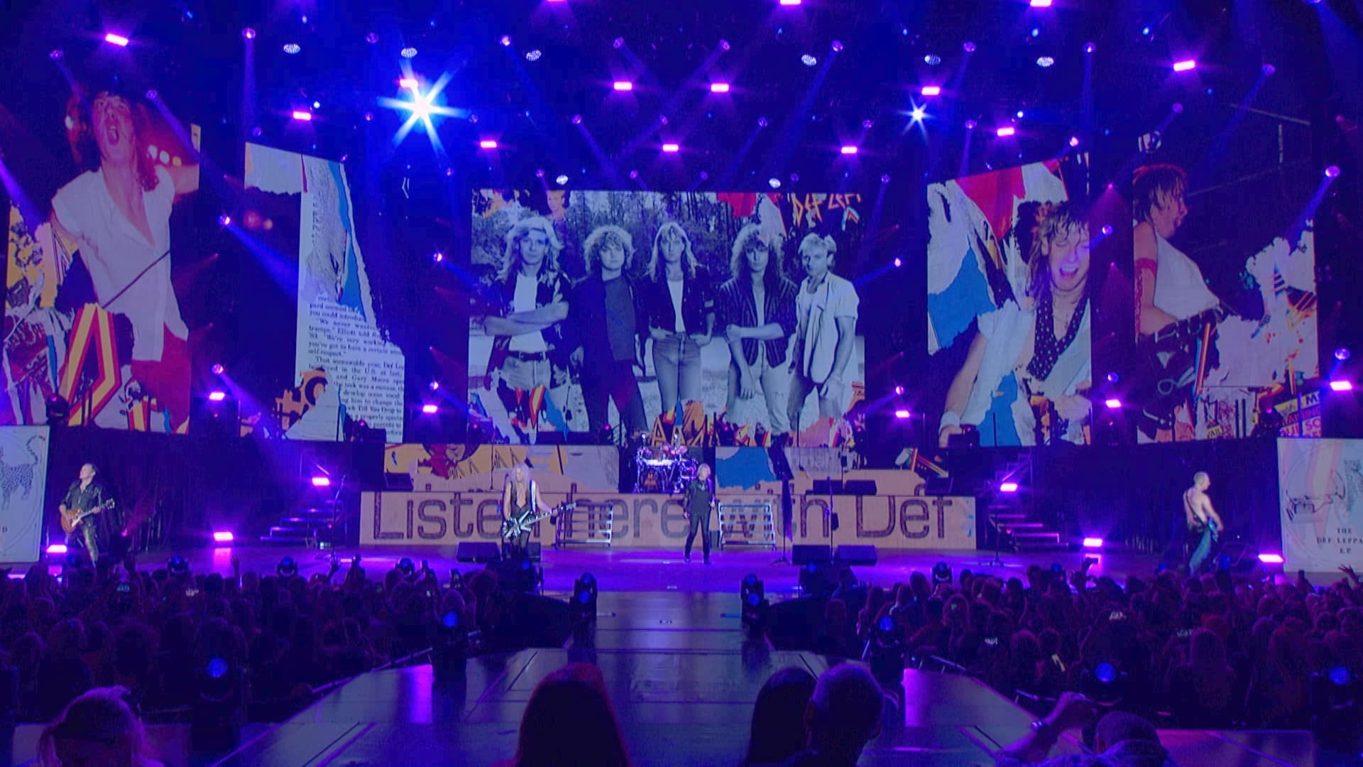 Concert stage with Def Leppard performing under purple lights. Large screens display retro-style images of people behind the band. Audience visible at the bottom.