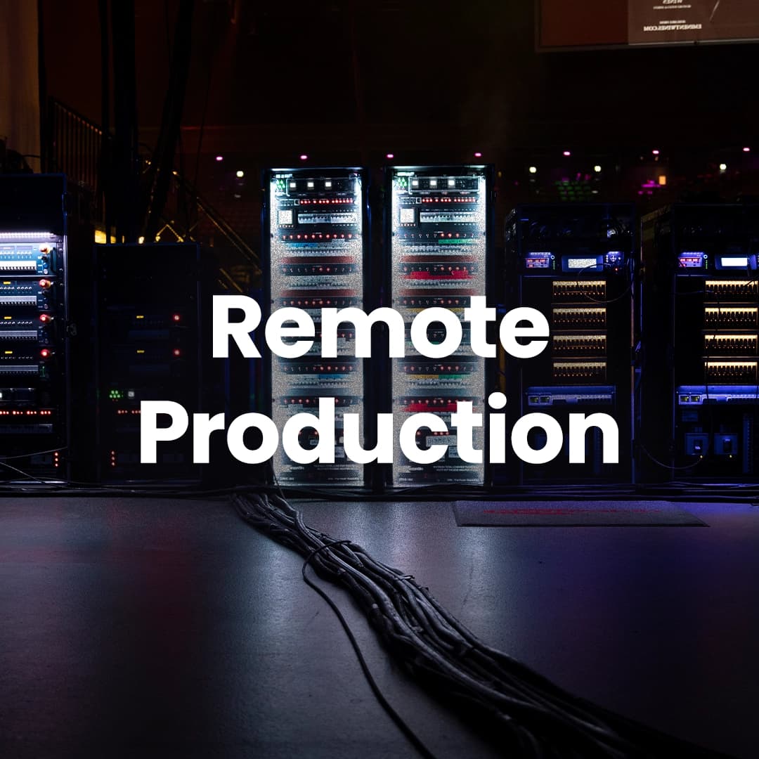 A dimly lit room with several racks of electronic equipment. Cables are visible on the floor. The words "Remote Production" are overlayed on the image.