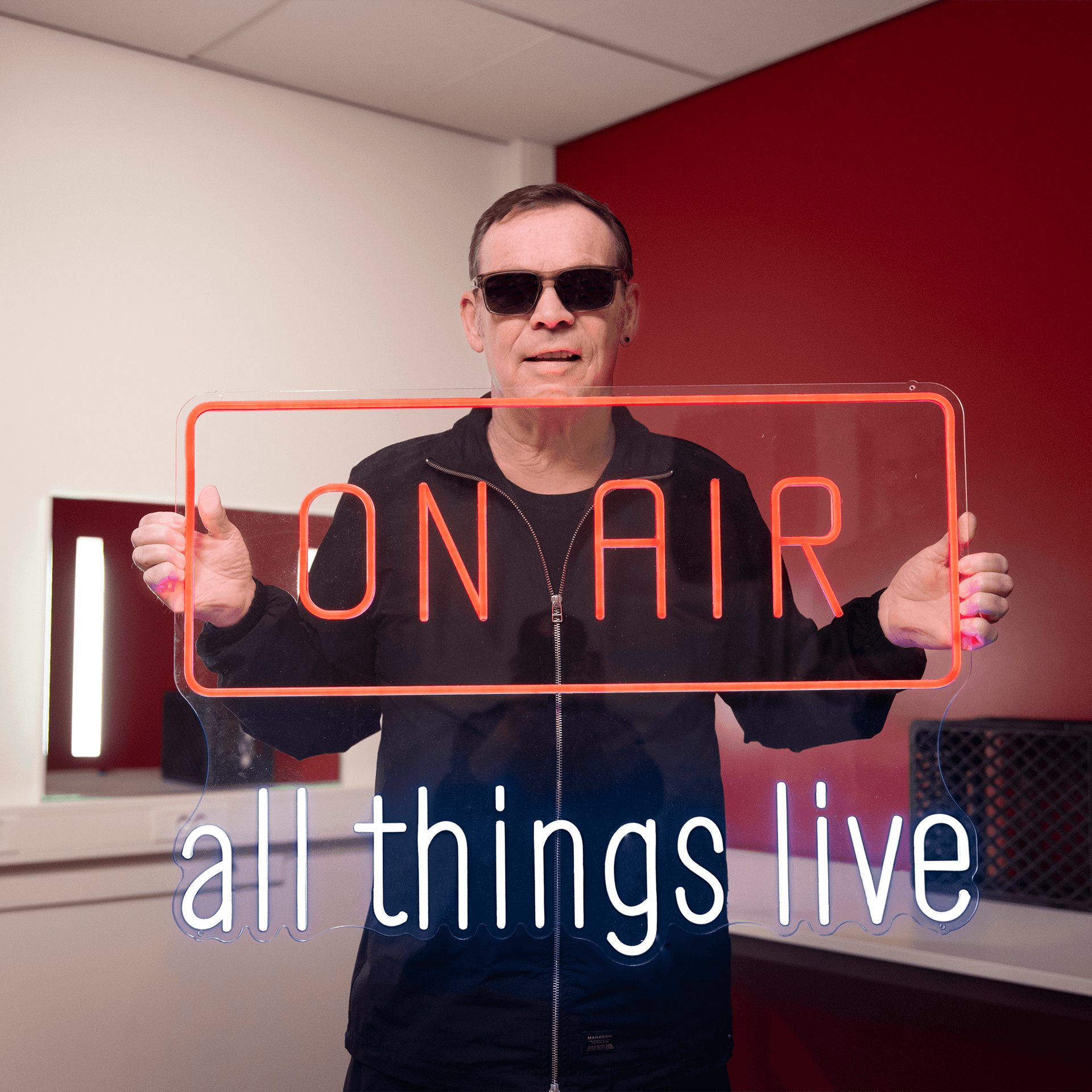 Ali Campbell holding an On Air neon sign