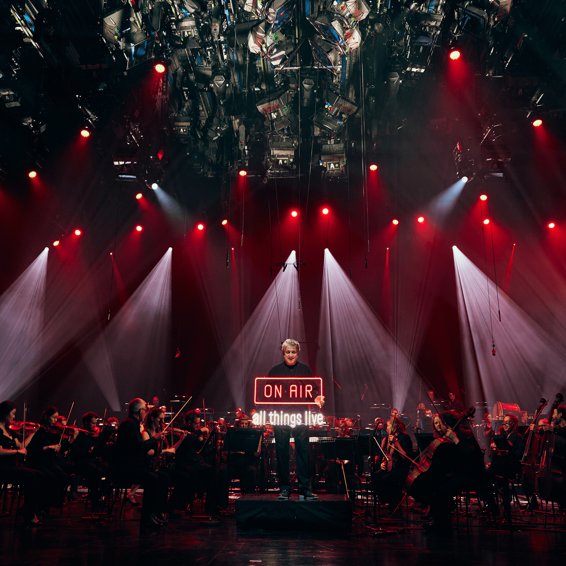 Conductor Peter Breiner holding an On Air neon sign with the Royal Philharmonic Orchestra behind him at the recording of the global livestream performances of Igor Stravinsky's The Firebird, Petrushka and the Rite Of Spring at BBC Television Centre