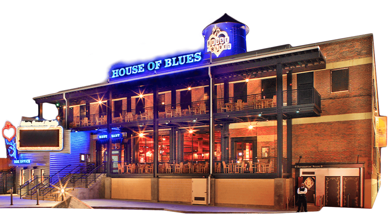 Exterior view of the House of Blues at night, with bright neon signage, outdoor balcony seating, and a brick facade.
