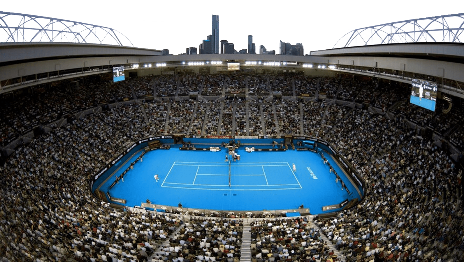 A large crowd fills the national tennis centre with a blue hardcourt tennis court at its center, city skyline visible in the background under an open roof.