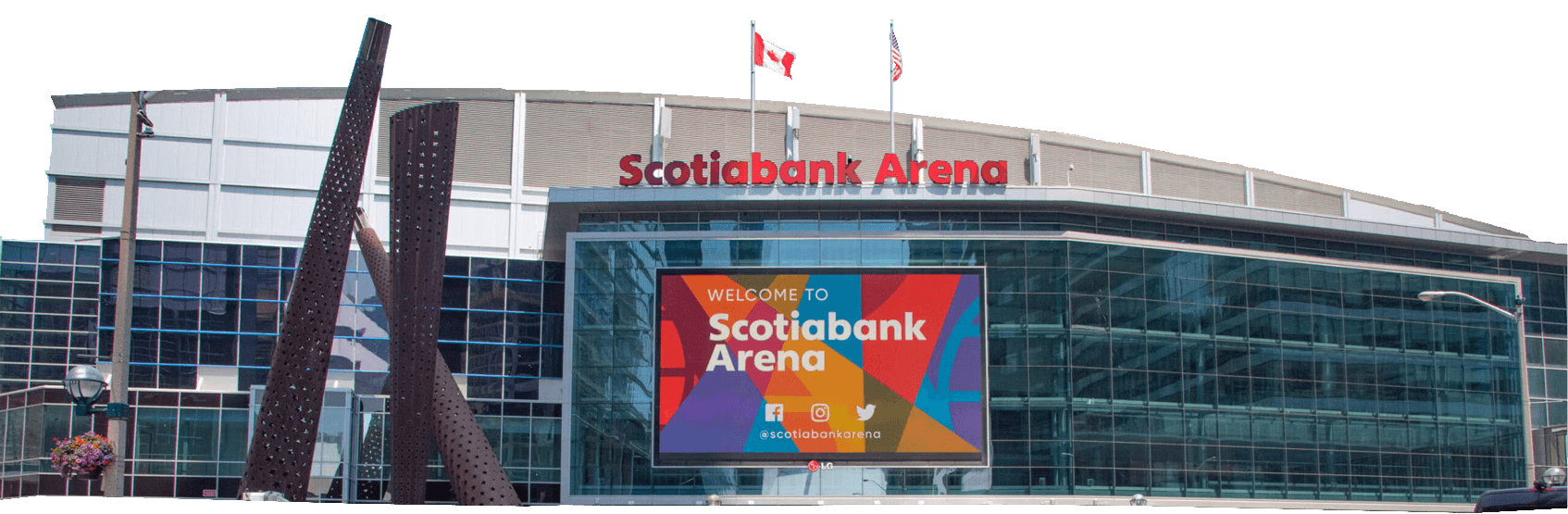 Exterior view of Scotiabank Arena with a large digital sign welcoming visitors; Canadian flags are visible on the roof and tall buildings in the background.