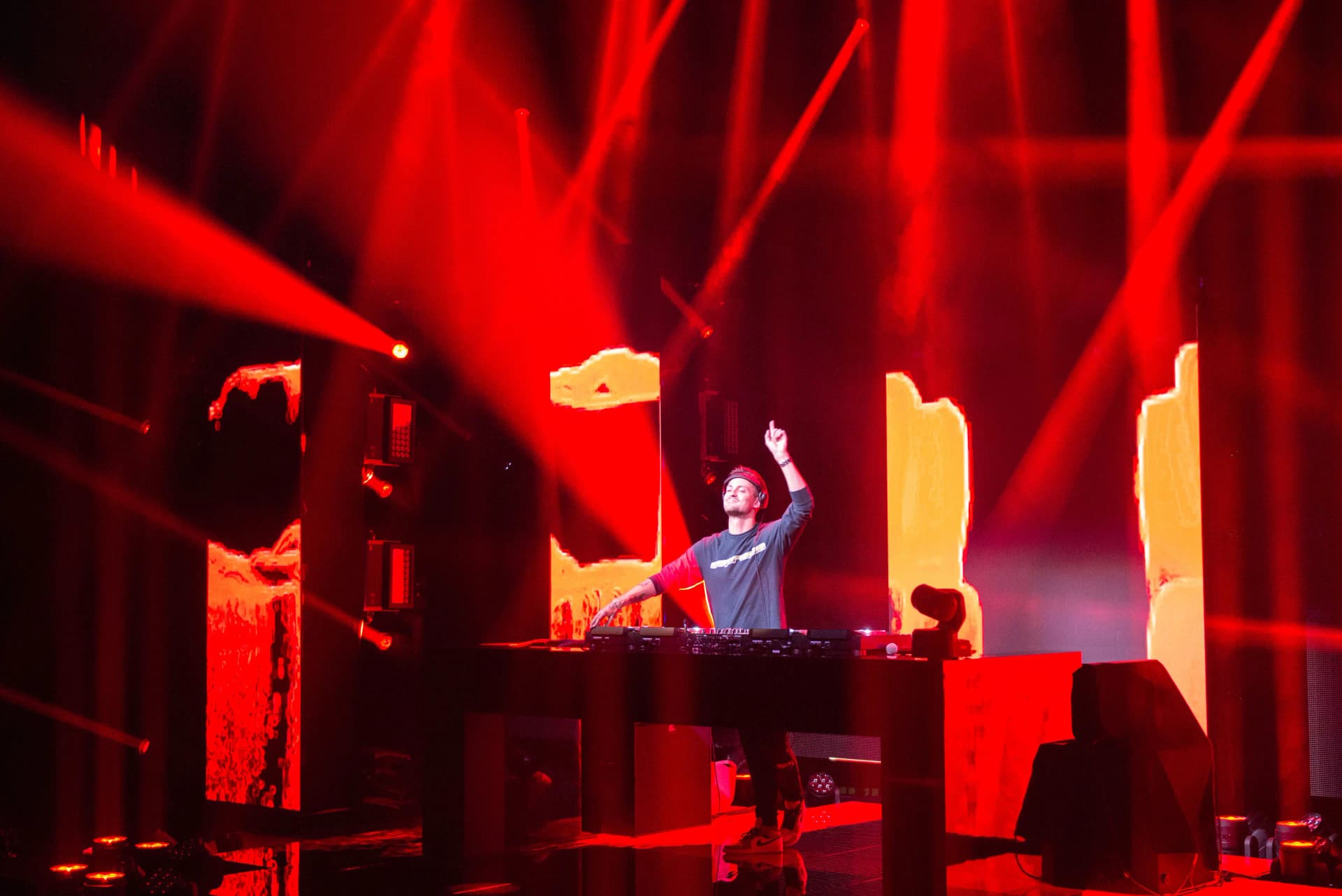 DJ Julian Jordan performing on stage with red lights and visuals.